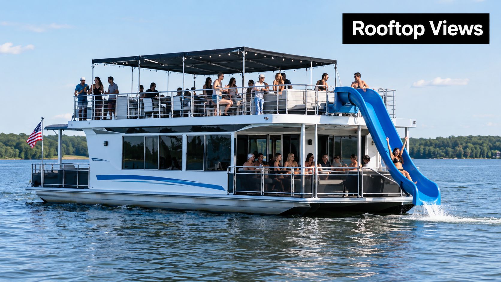 A large multi-level party boat with a water slide full of people enjoying a sunny day.