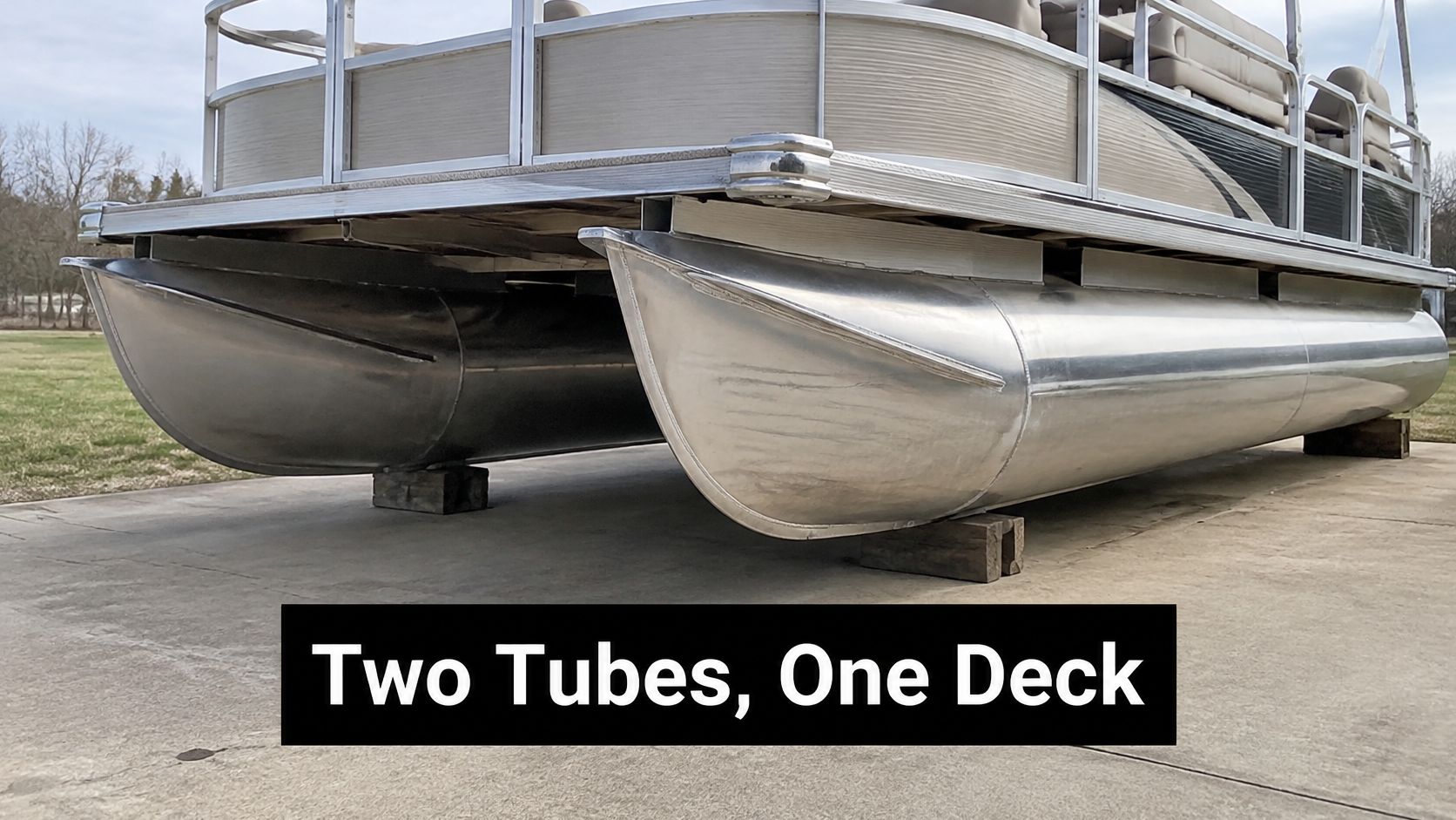 A close-up view of the two aluminum pontoons supporting the deck of a pontoon boat on land.