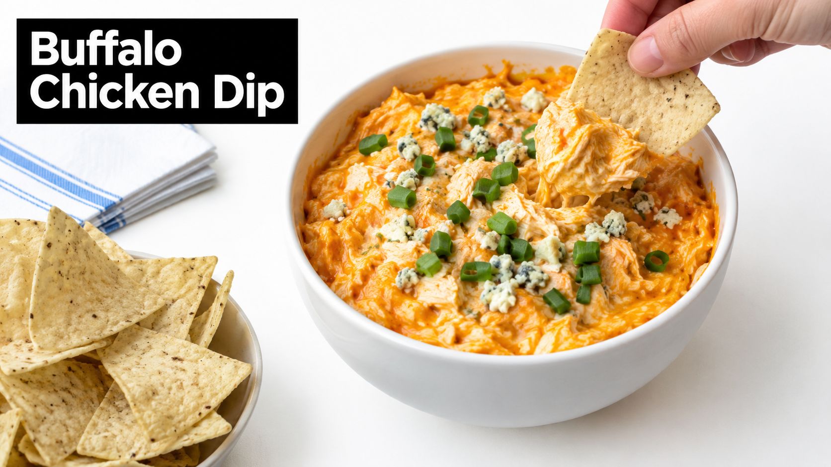 A hand dipping a tortilla chip into a creamy, orange buffalo chicken dip with blue cheese crumbles.