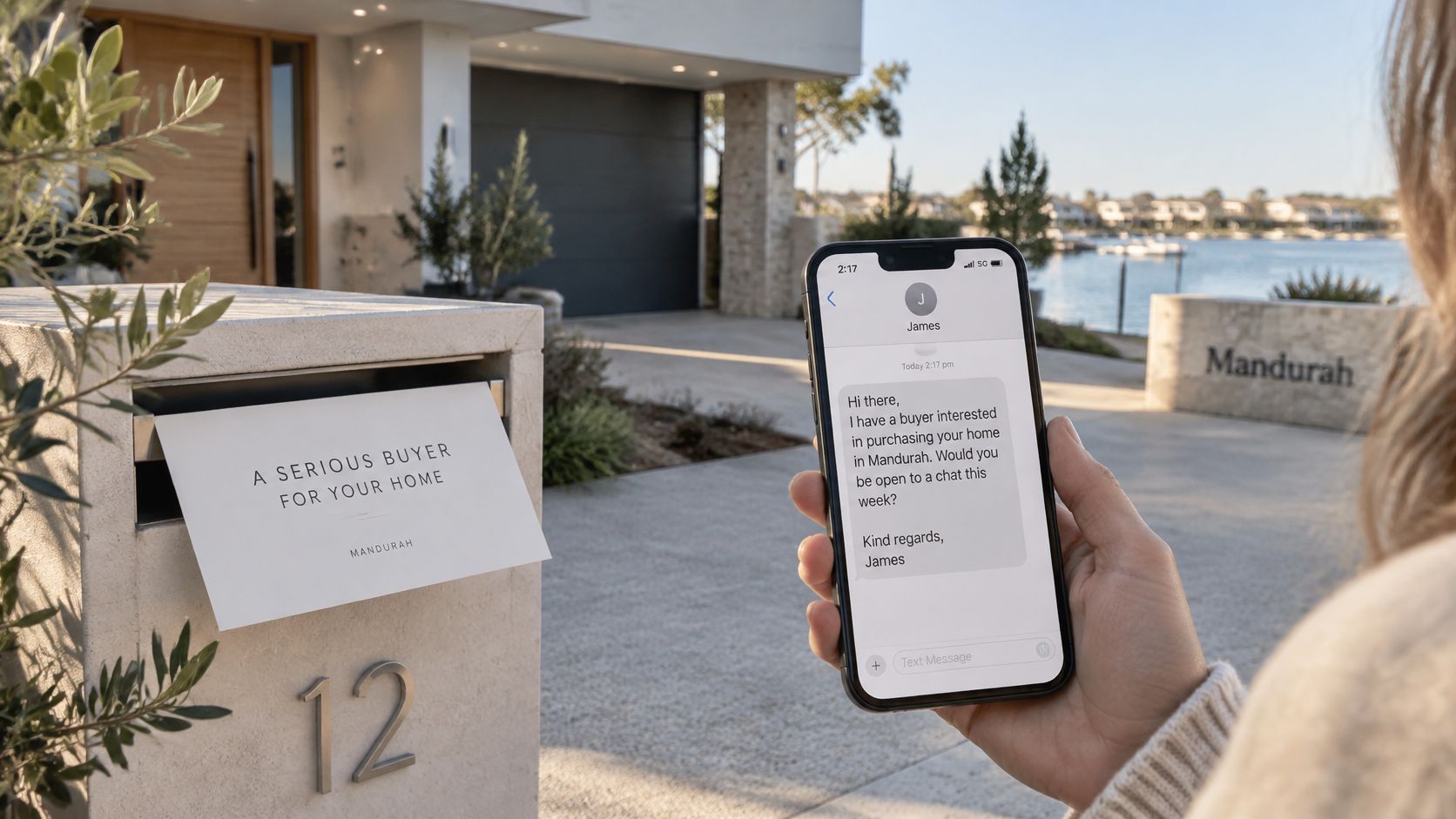 A person holding a smartphone showing a real estate inquiry message in front of a modern house.