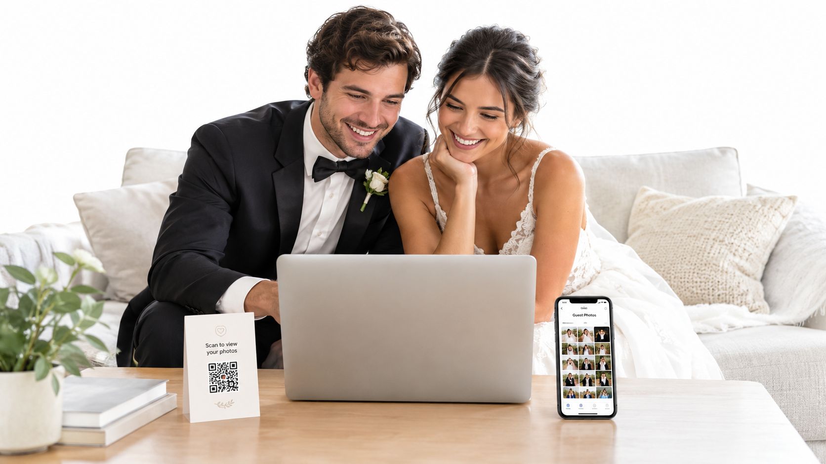 A happy bride and groom look at their wedding photos together on a laptop and smartphone.