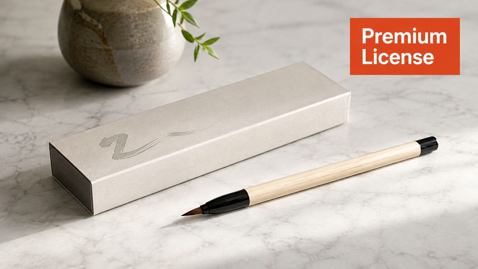 A Japanese style calligraphy brush rests on a marble countertop next to its elegant beige storage box.