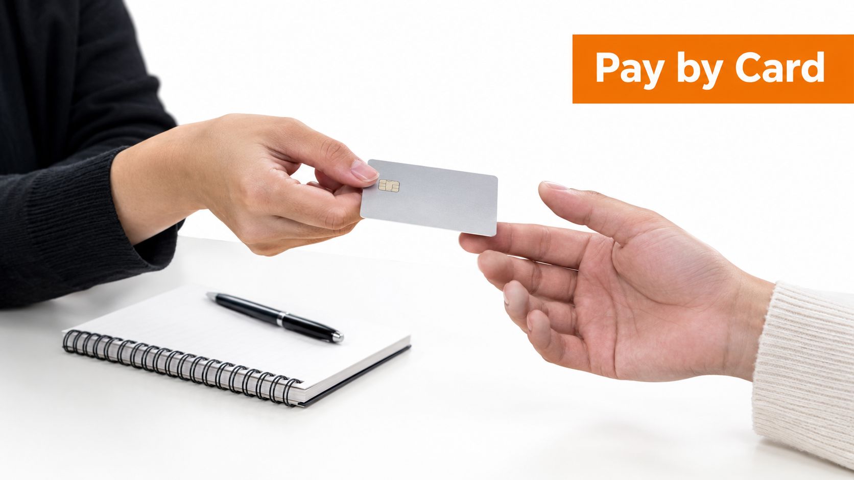 A close-up view of a person handing a gray credit card to another person for payment.
