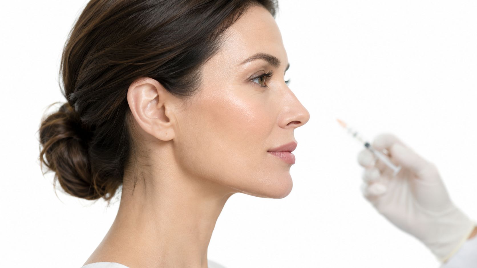 A dermatologist prepares to perform a cosmetic facial filler injection on a woman's face.