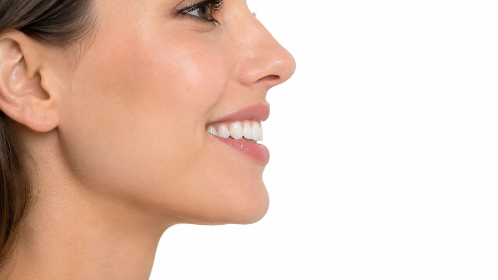 A close-up profile view of a young woman with a natural, aesthetic smile showing straight white teeth.