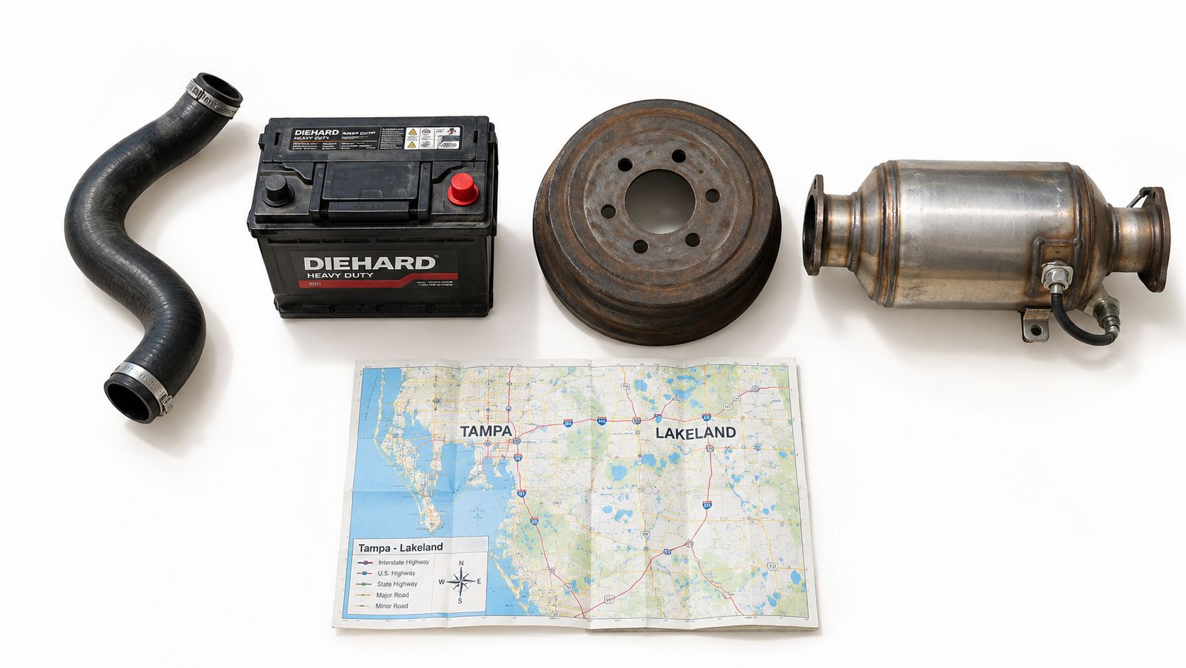 Automotive repair parts including a battery, radiator hose, brake drum, exhaust component, and a road map.