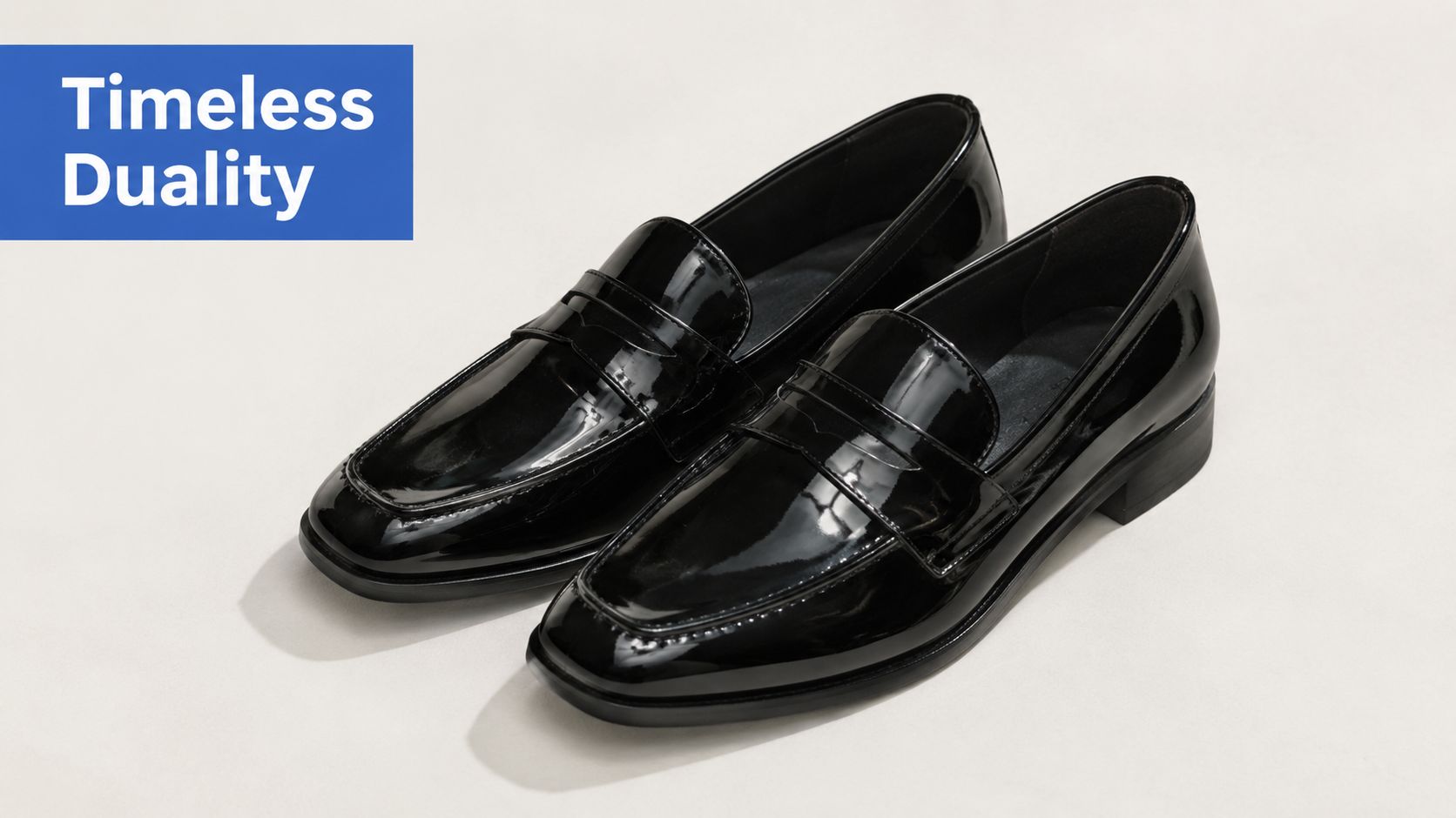 A pair of shiny black patent leather loafers isolated on a plain light beige background.