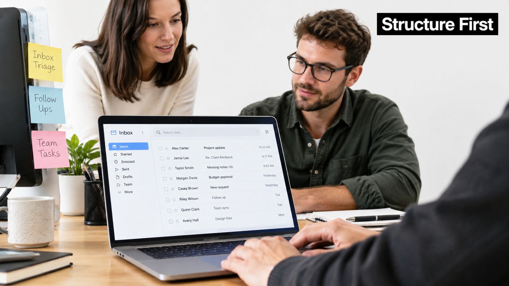 A professional team collaborating around a laptop to manage email inbox tasks efficiently in an office.