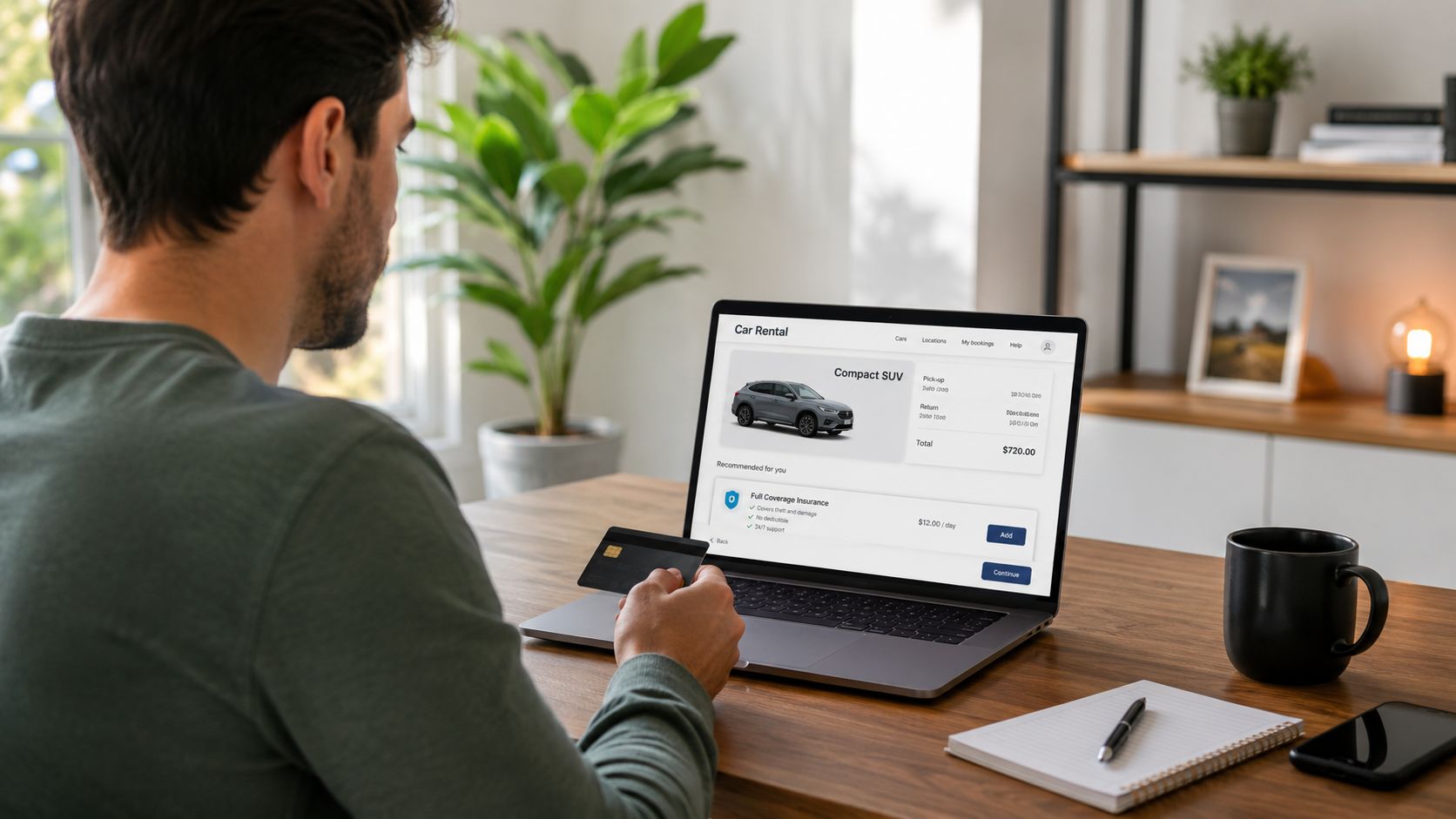 Un homme réserve une voiture de location sur son ordinateur portable en tenant une carte bancaire.