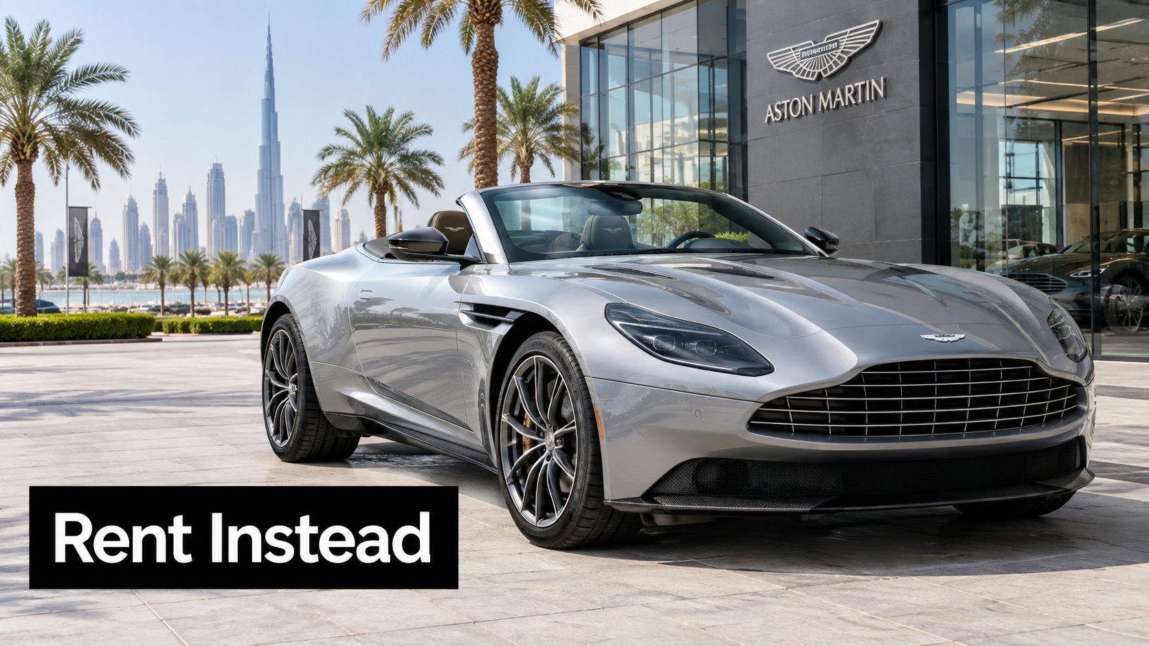 Aston Martin Price in Dubai: Full 2026 Buying & Rental Guide 3 A silver Aston Martin convertible parked in front of an Aston Martin showroom in Dubai with skyscrapers.