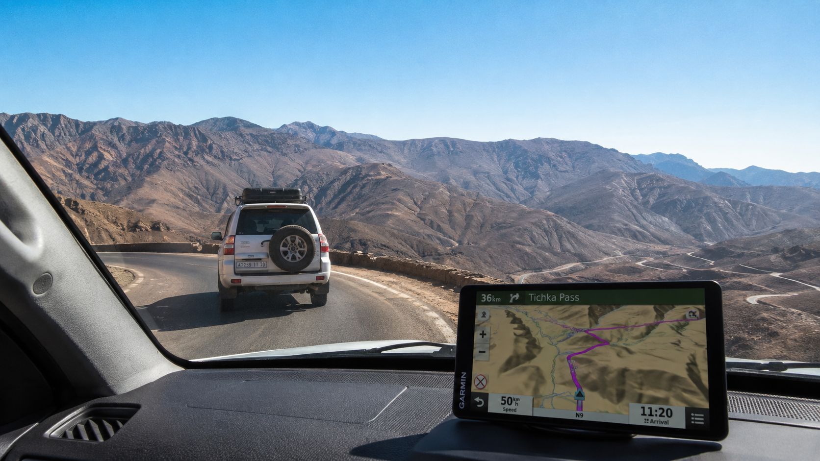 Vue depuis une voiture sur une route de montagne sinueuse avec un GPS affichant le col Tizi-n-Test.
