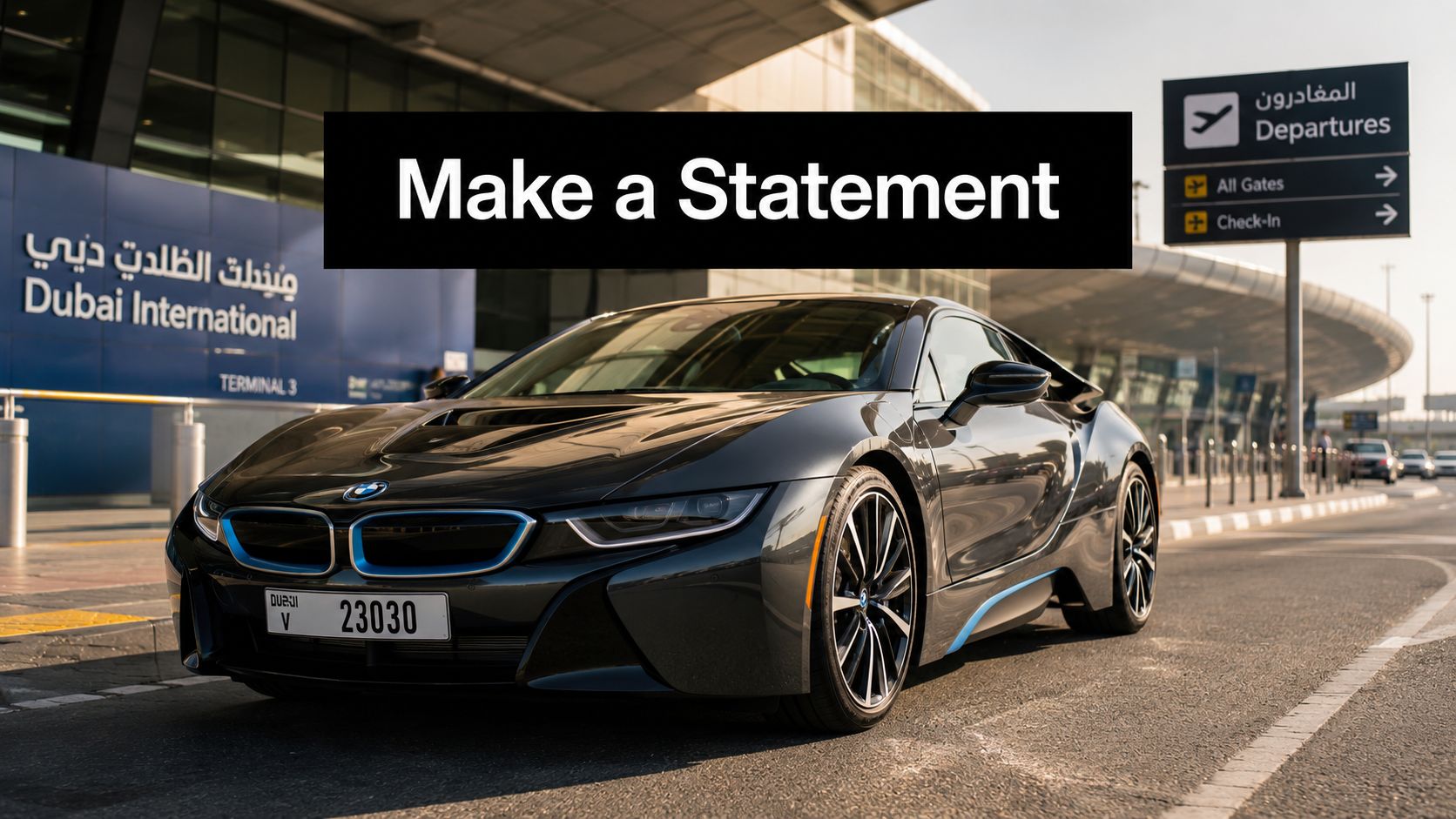 A sleek dark grey BMW i8 parked outside the modern Dubai International Airport Terminal 3 departure entrance.