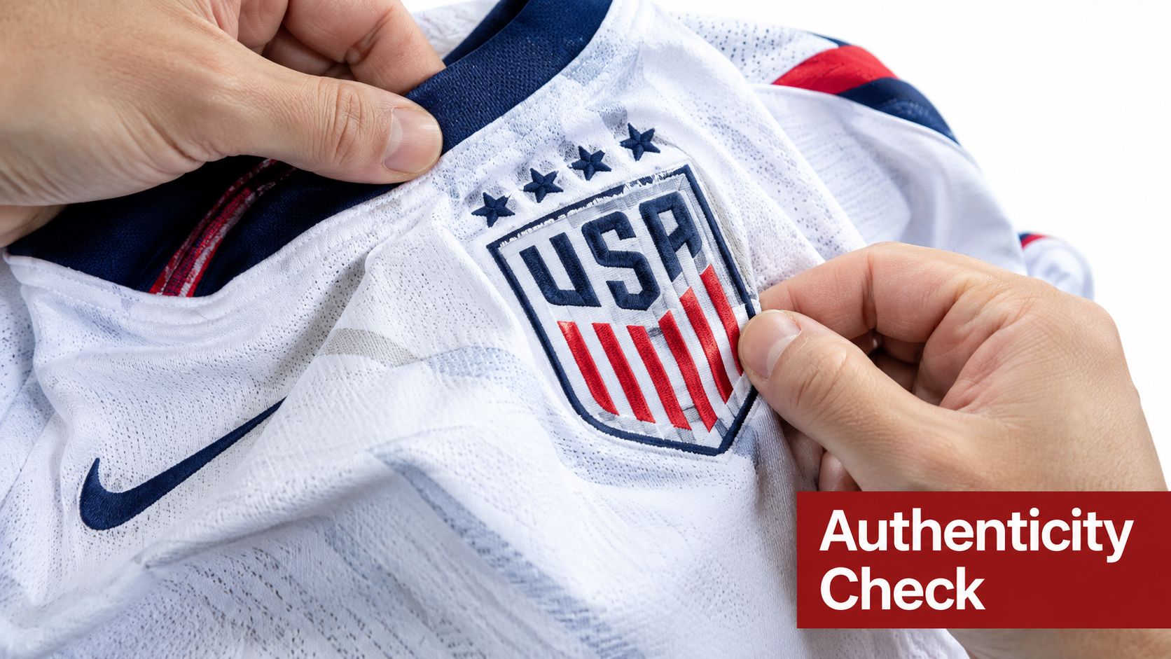 A close-up view of hands inspecting the embroidered USA crest on a white Nike soccer jersey.
