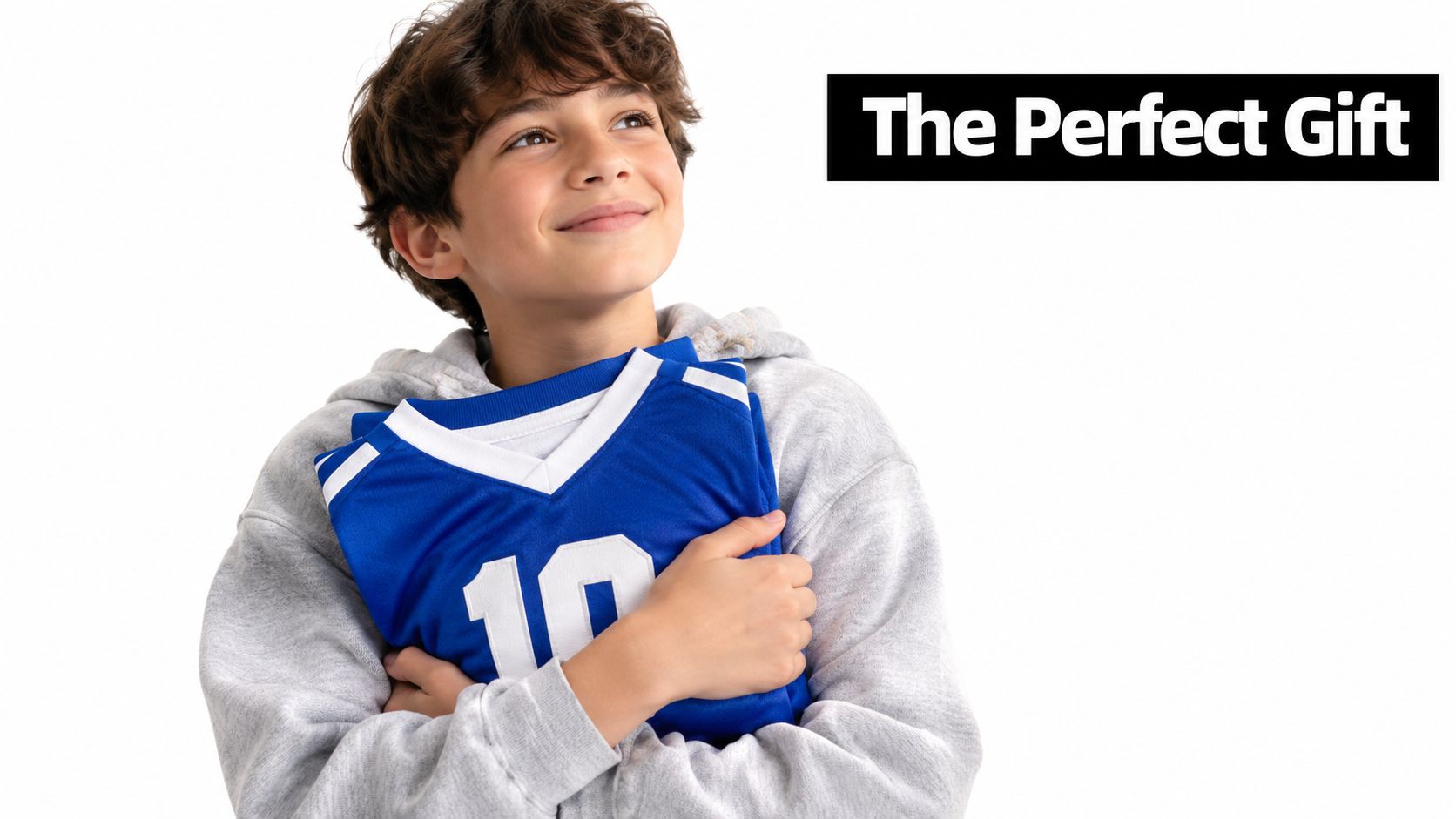 A young boy smiling happily while hugging a blue number ten sports jersey as a gift.