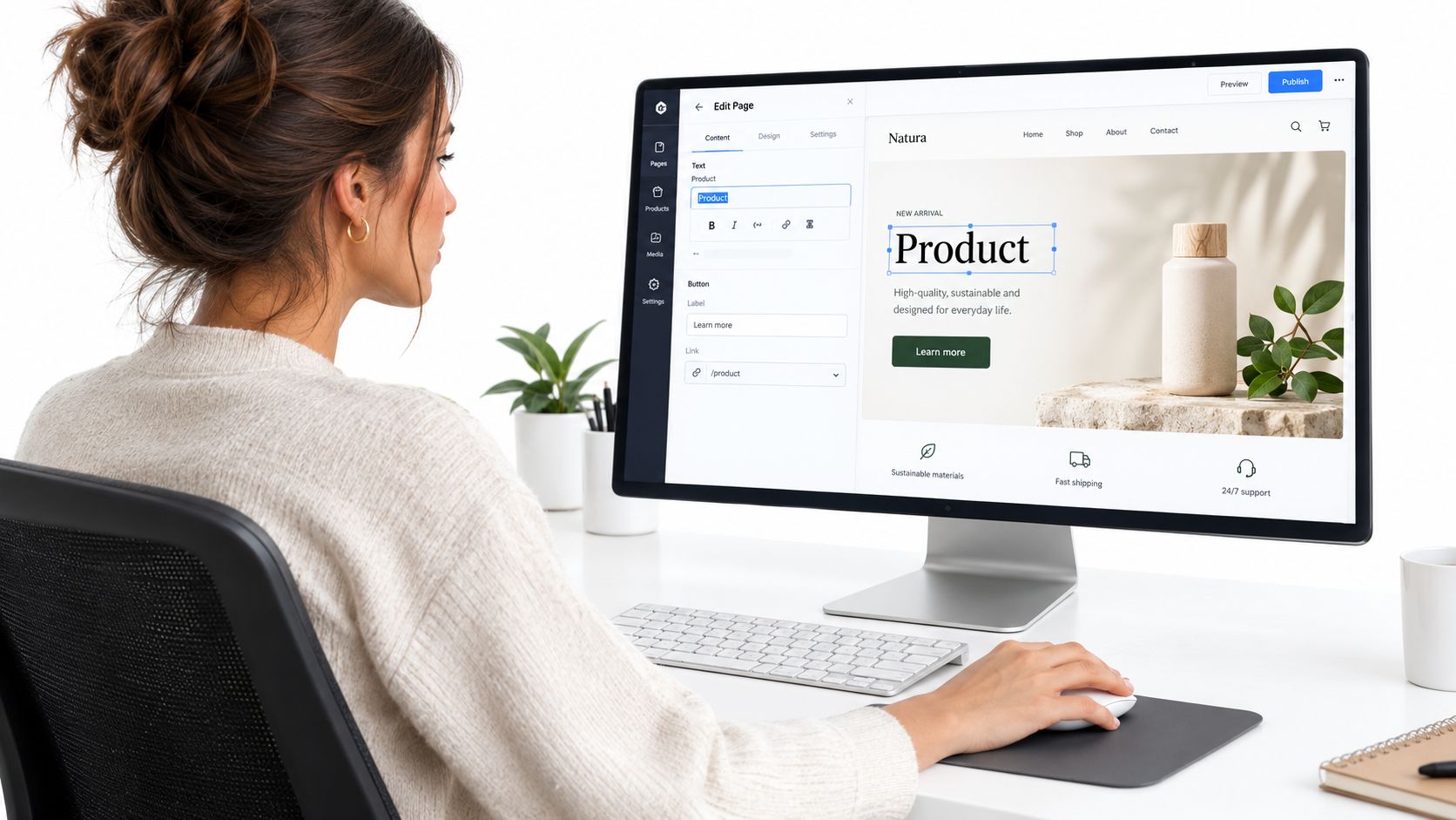 A woman designing a website layout using a WYSIWYG editor on her computer in a bright office.