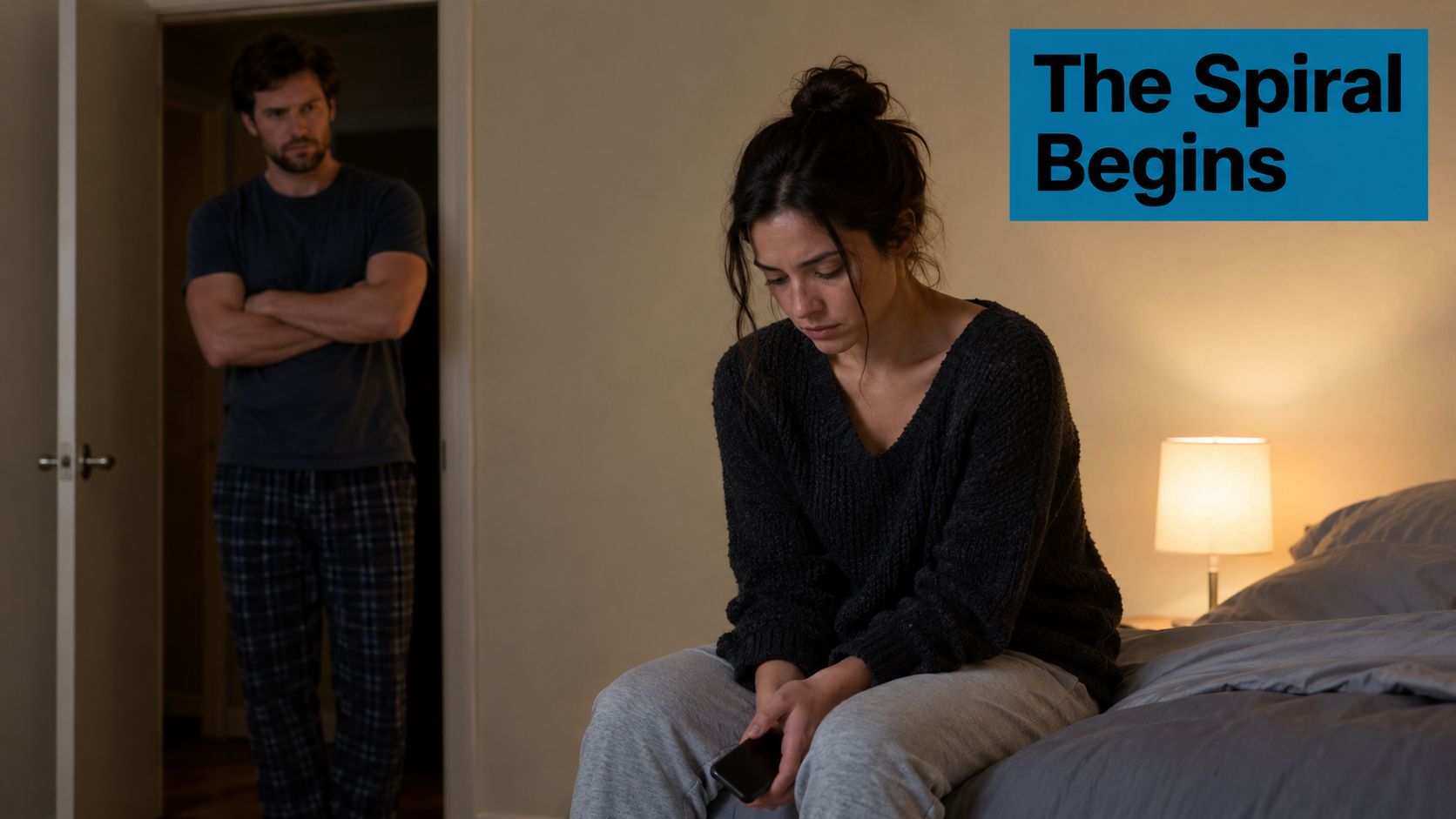 A couple experiencing tension in their relationship while sitting in a dimly lit bedroom together.