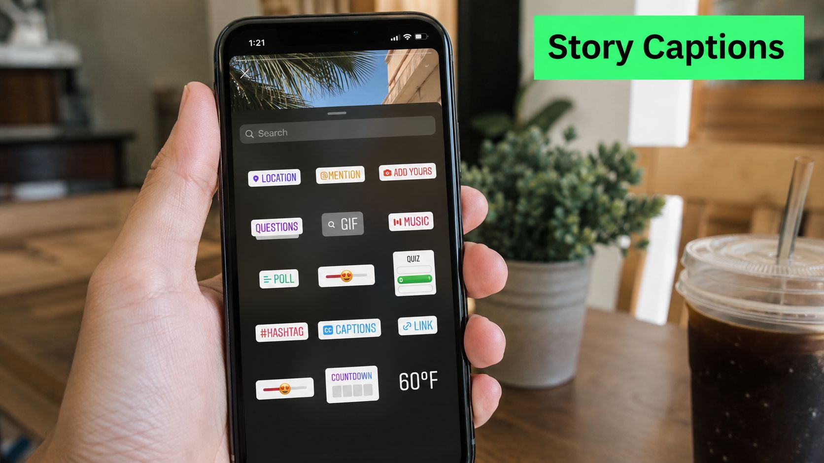 A hand holding a smartphone displaying the Instagram stories sticker menu with the captions option highlighted.