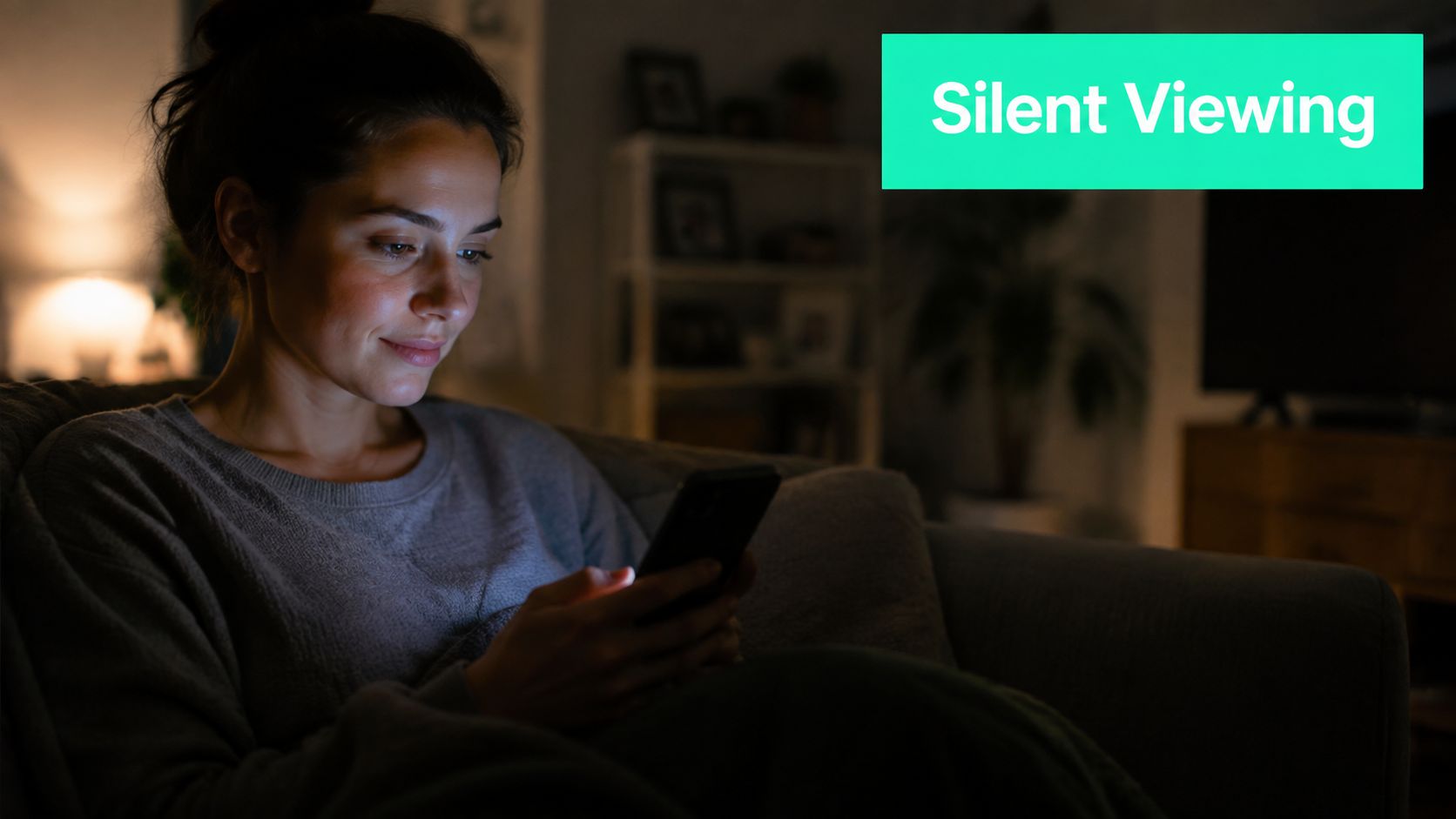 A young woman sitting on a comfortable couch at night, looking at her smartphone screen in the dark.