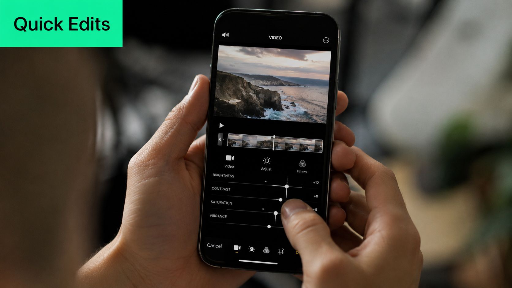 A person uses their fingers to adjust video editing settings on a smartphone screen showing a coastline.