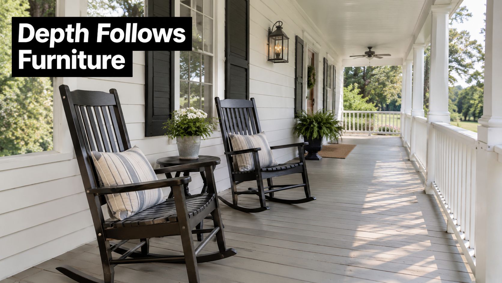 A scenic farmhouse wrap around porch featuring two classic black wooden rocking chairs and potted greenery.