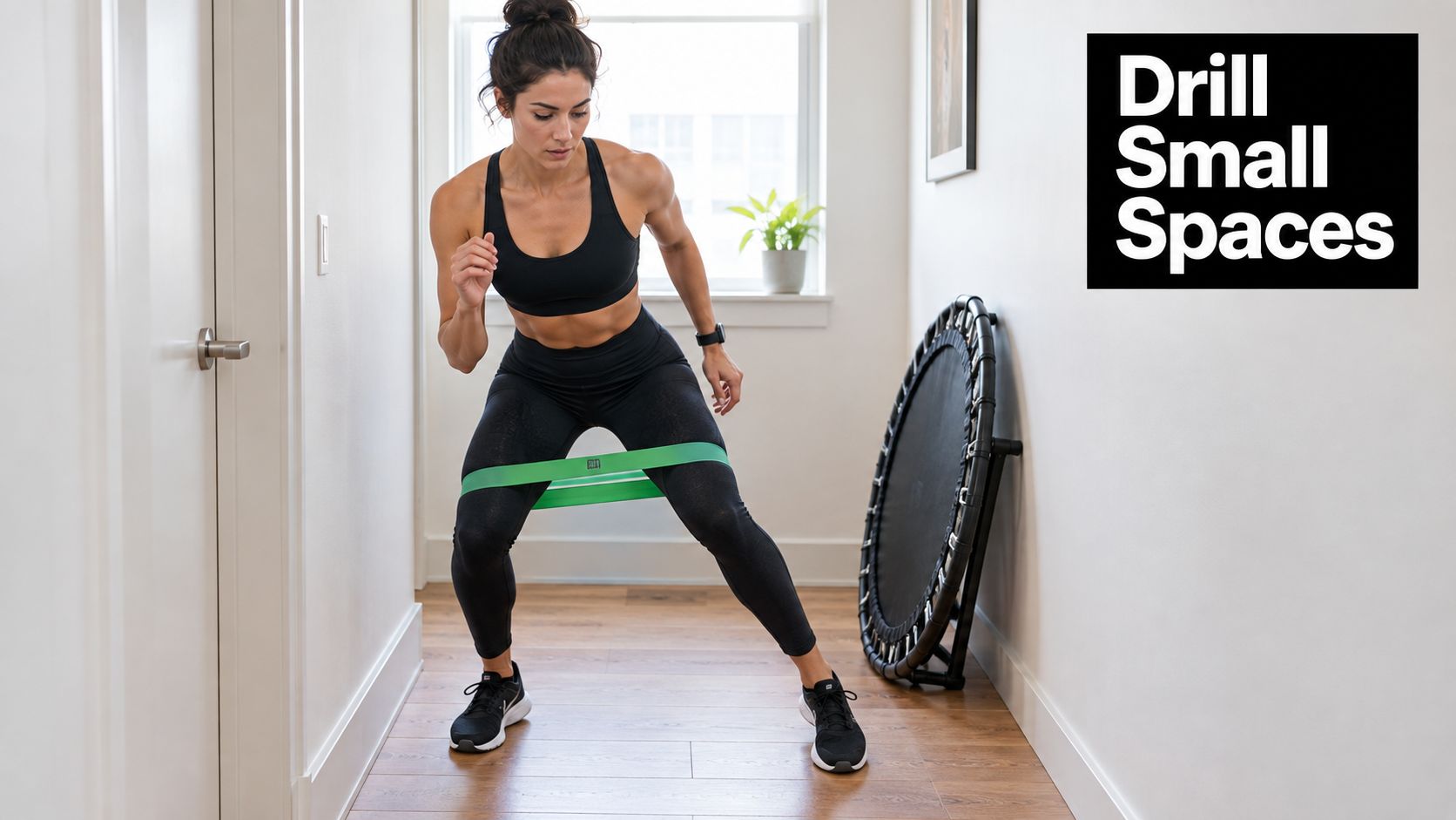 A woman exercising in a hallway using a green resistance band around her thighs for leg workout.
