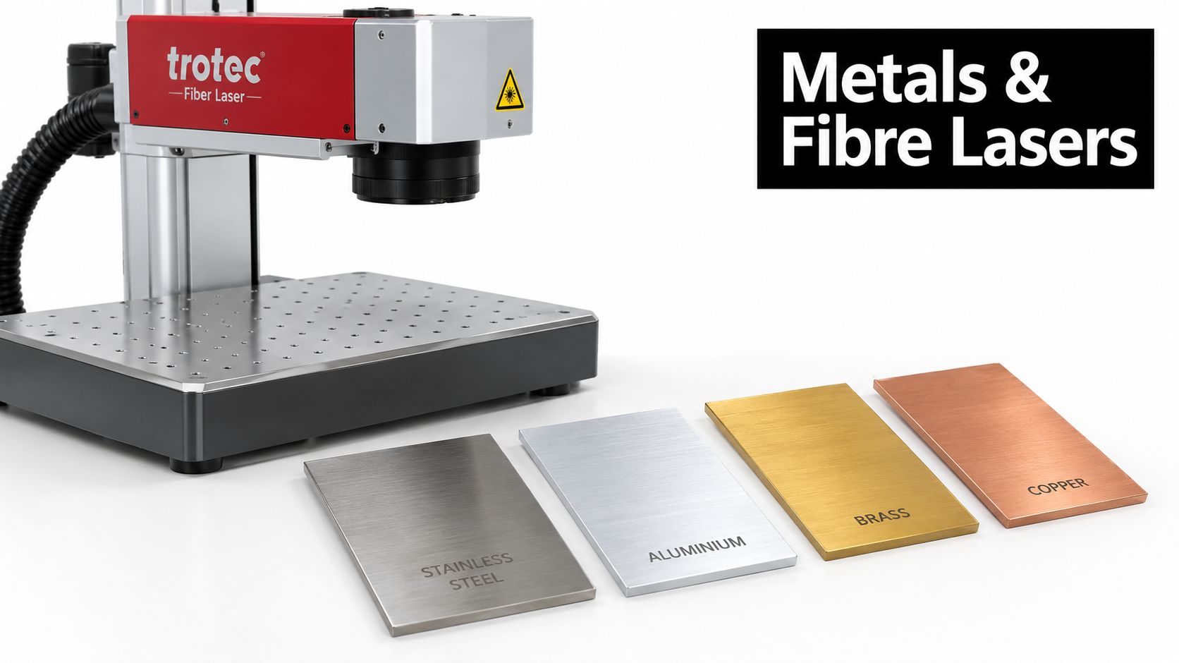 A professional Trotec fiber laser machine positioned next to metal samples of stainless steel, aluminium, brass, and copper.