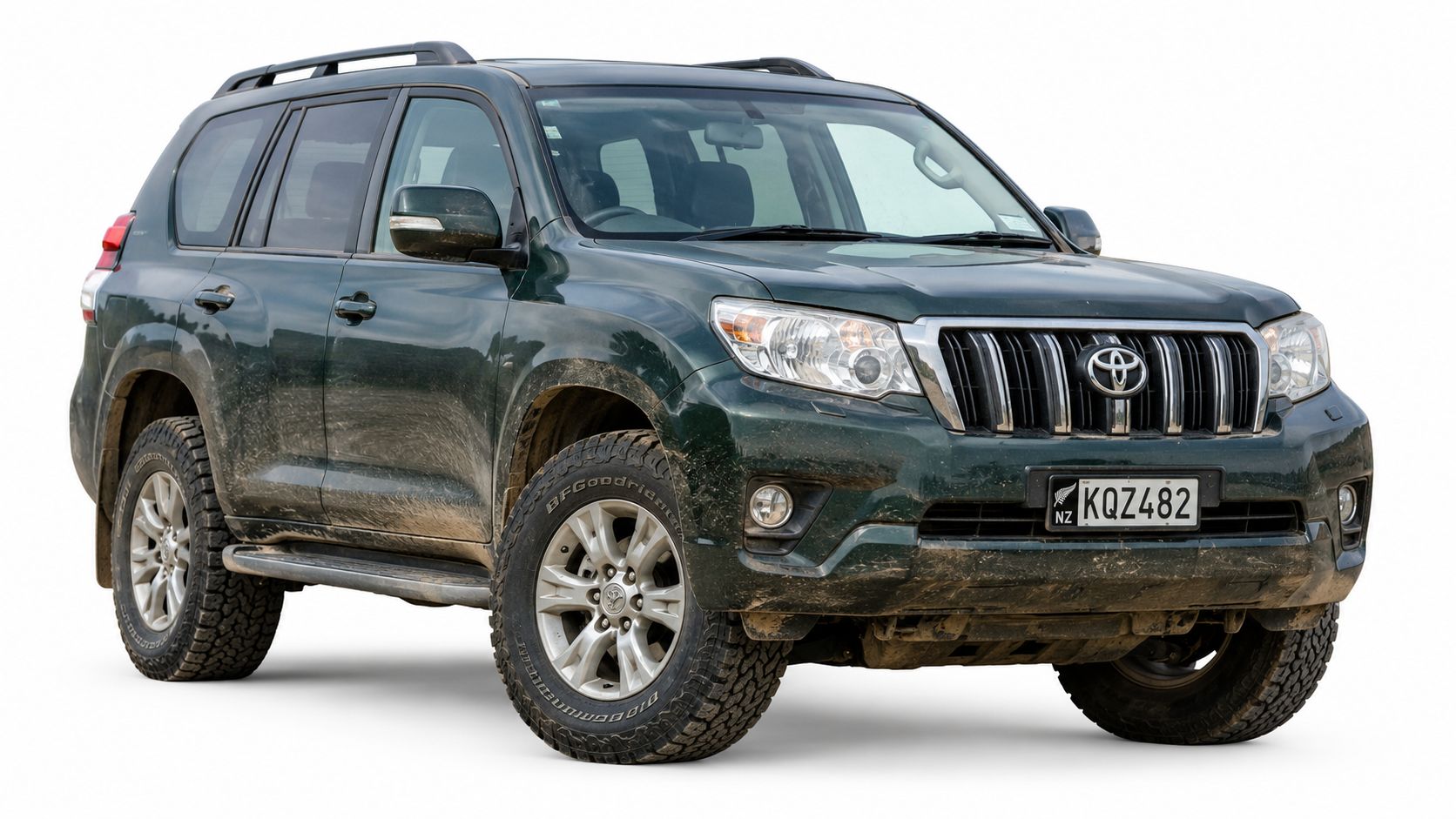 A dirty dark green Toyota Land Cruiser Prado SUV parked against a plain white studio background.
