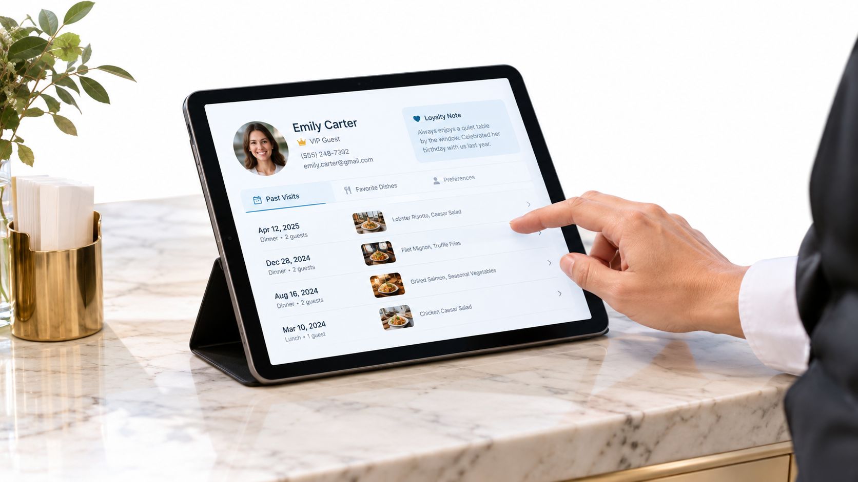 A tablet screen displaying a customer profile with booking history on a marble countertop surface.