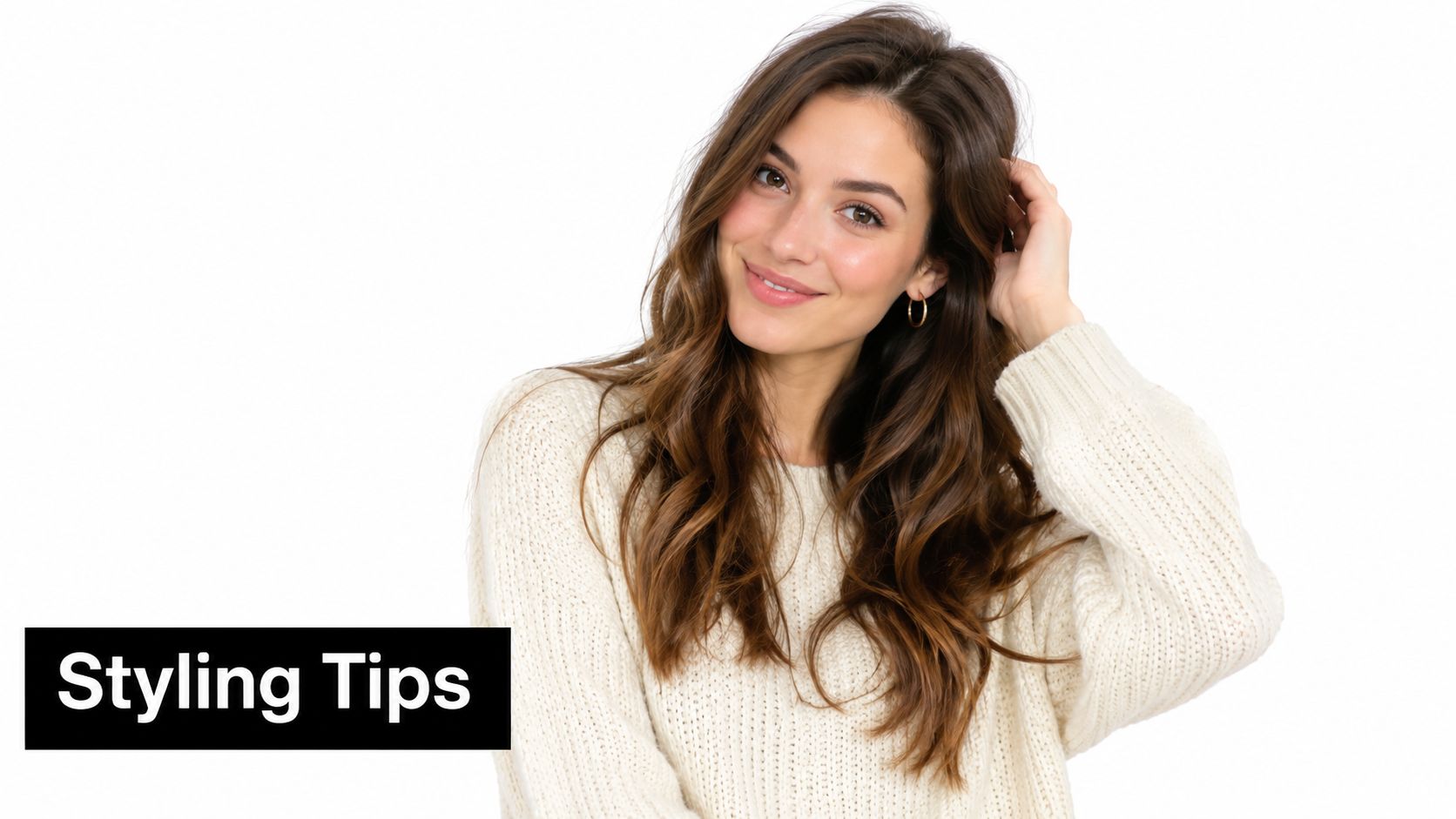 A beautiful young woman with long wavy brown hair wearing a white cable knit sweater posing smilingly.