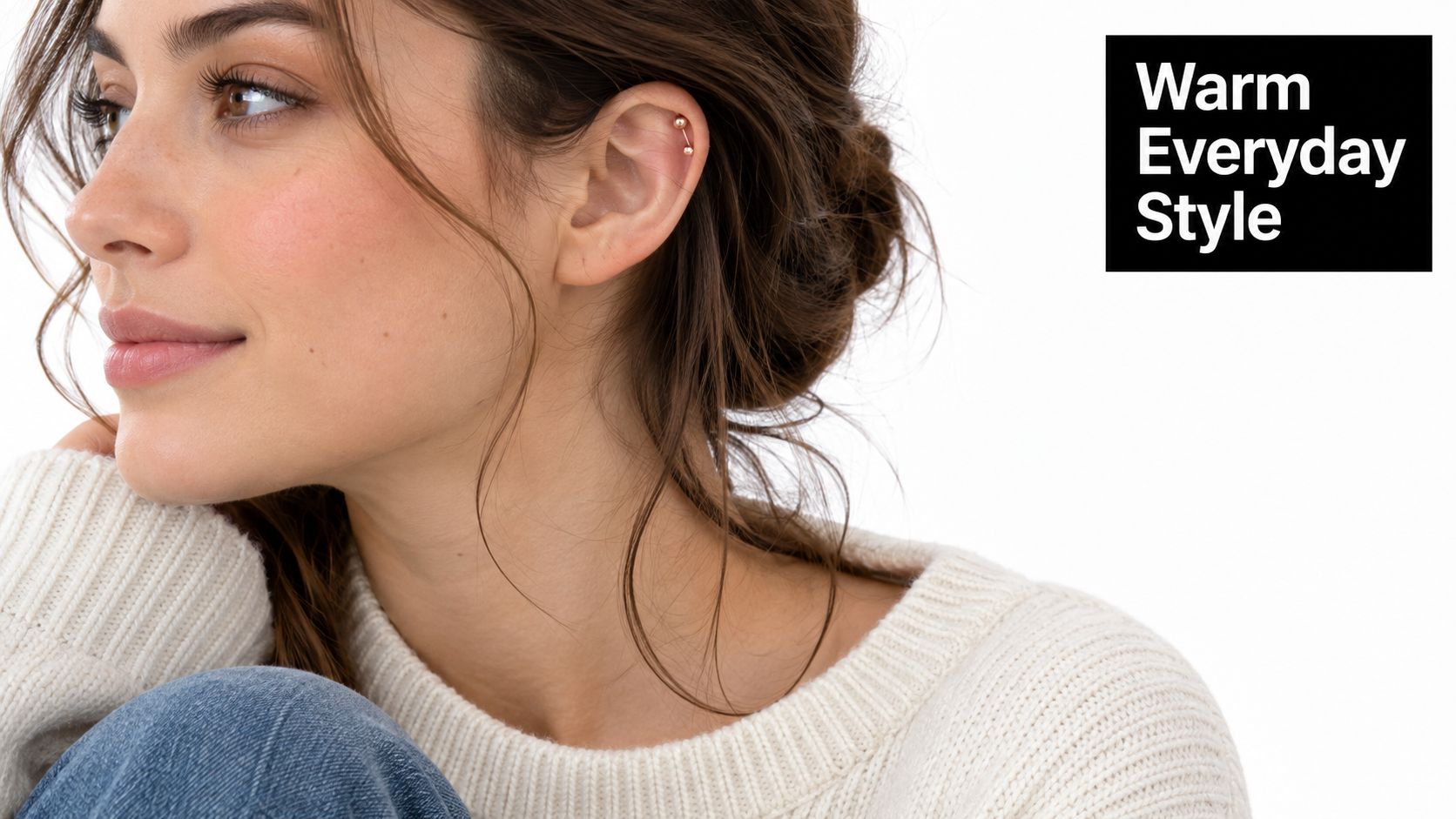 A close-up of a woman wearing a minimalist rose gold barbell piercing in her upper ear cartilage.
