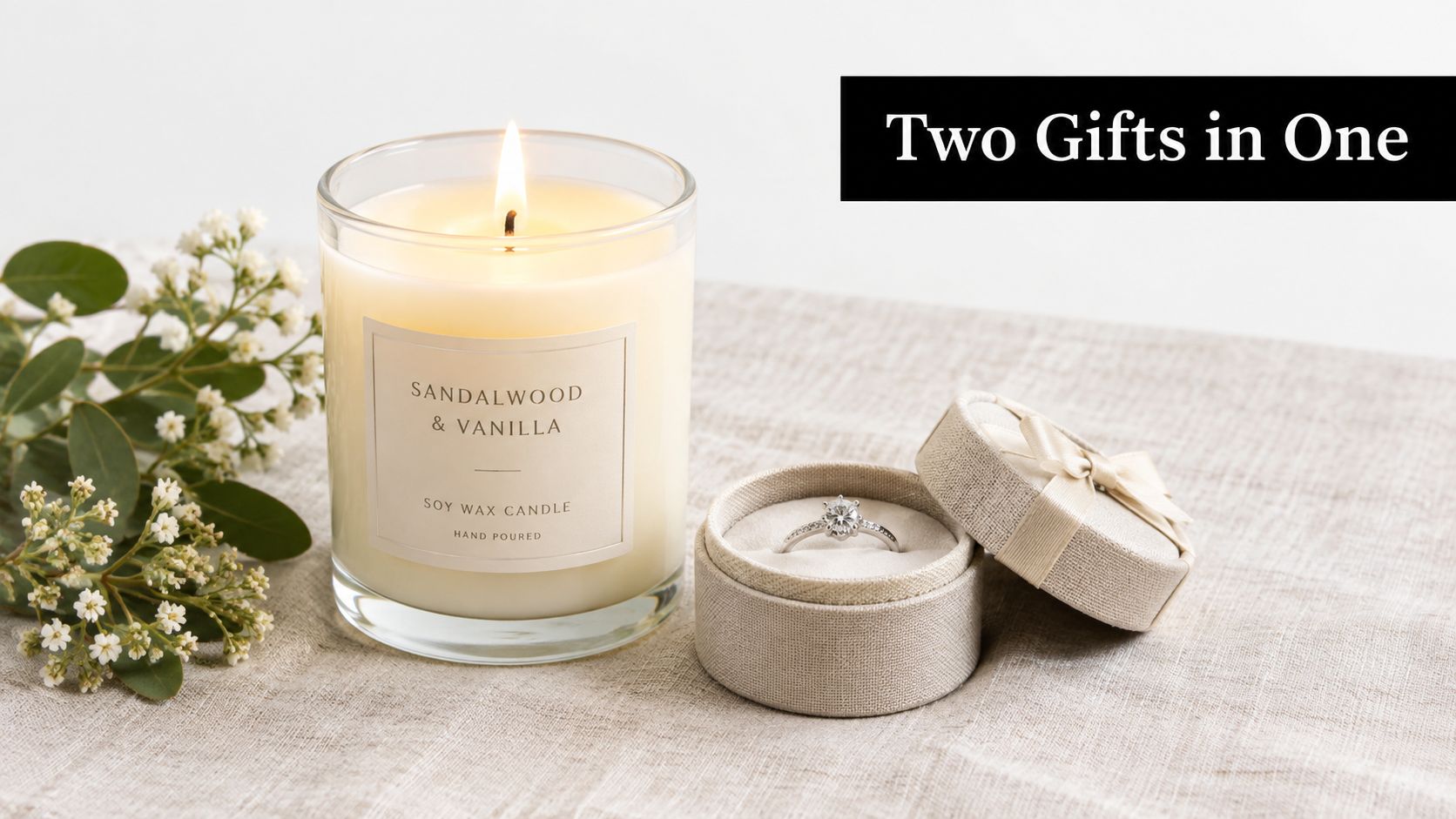 A lit sandalwood and vanilla soy candle next to a ring box containing a diamond engagement ring.