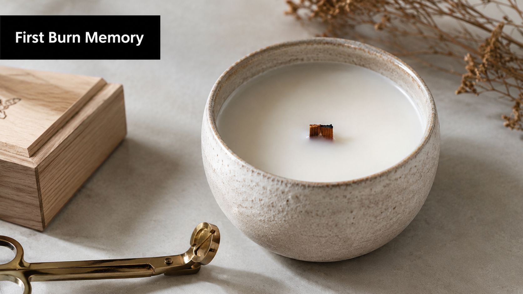 A minimalist luxury soy candle in a ceramic bowl placed next to brass wick trimmers on a table.