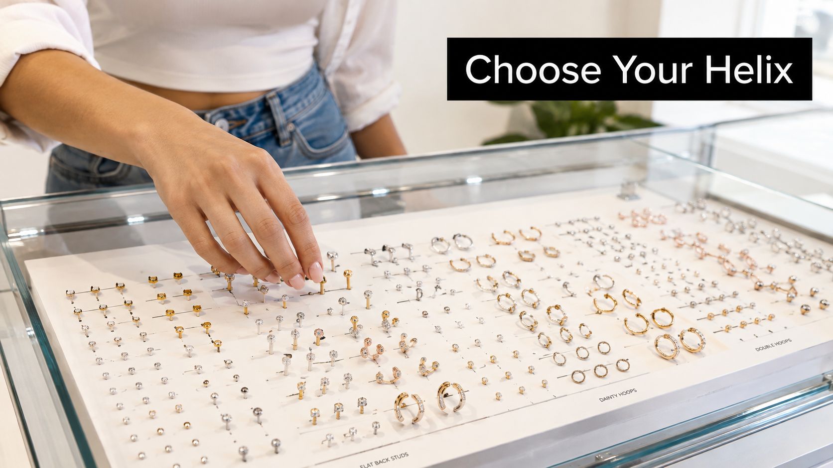 A customer browsing through a glass display case filled with a variety of stylish helix piercing jewelry.