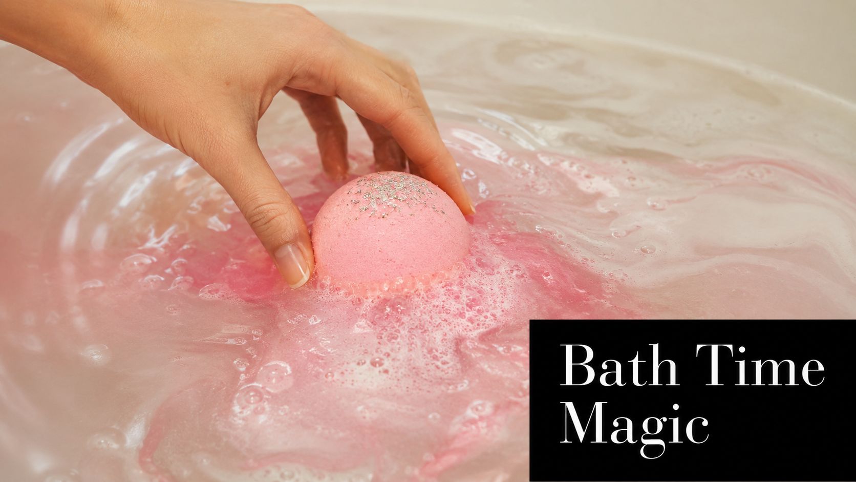 A hand placing a pink, glitter-topped bath bomb into warm water, creating a swirling, vibrant pink foam.
