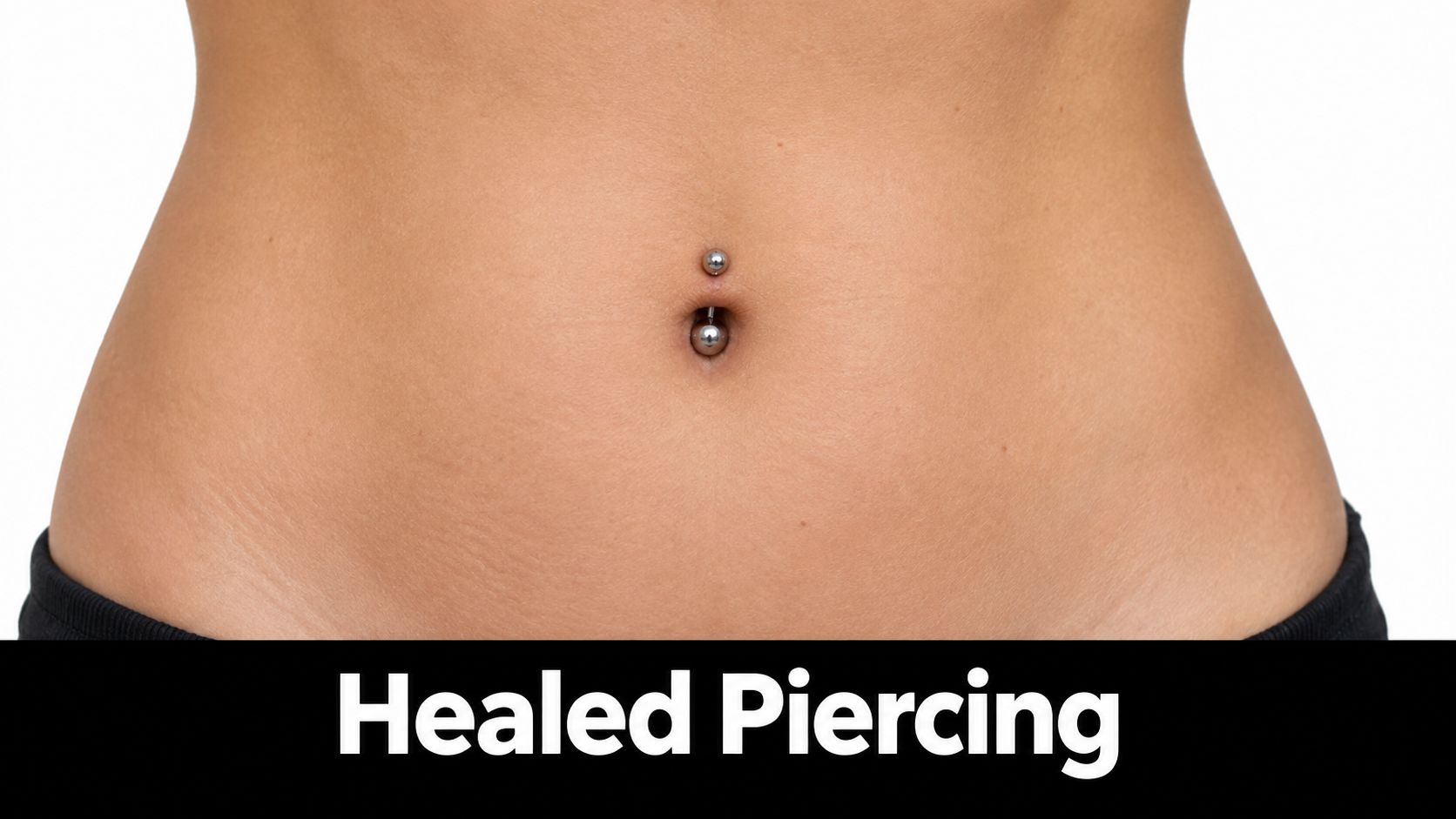 A close-up view of a woman's stomach showing a clean, well-healed navel piercing with silver jewelry.