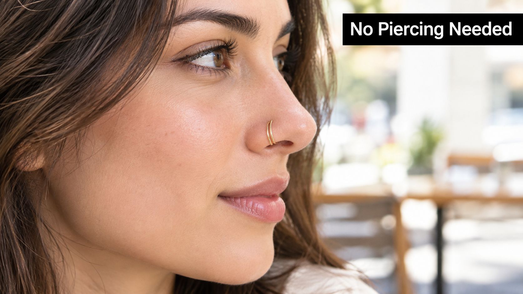 A close-up profile view of a woman wearing a gold double hoop faux nose ring cuff.