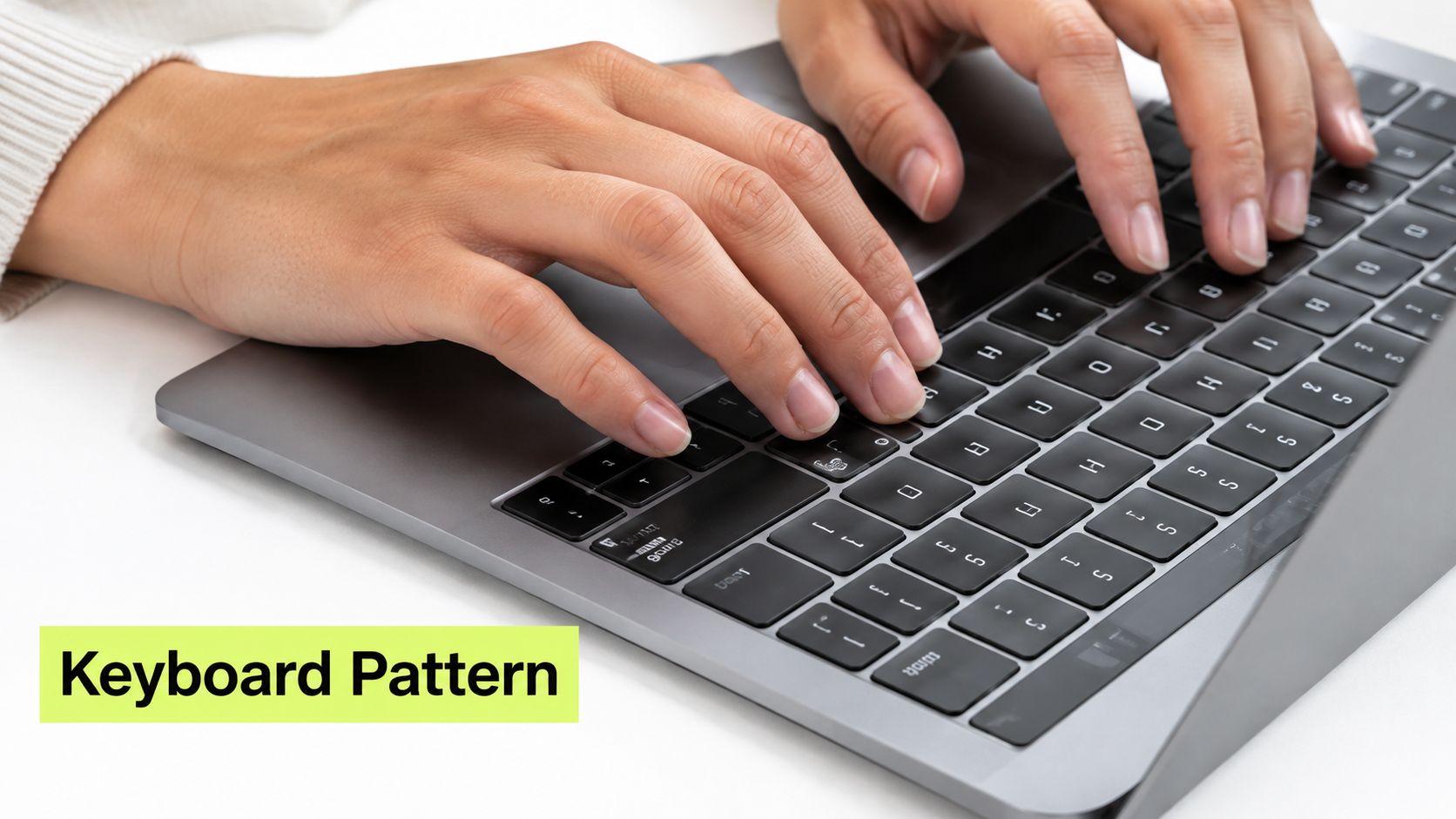 A close-up view of hands typing on a laptop keyboard to illustrate alphanumeric password entry.
