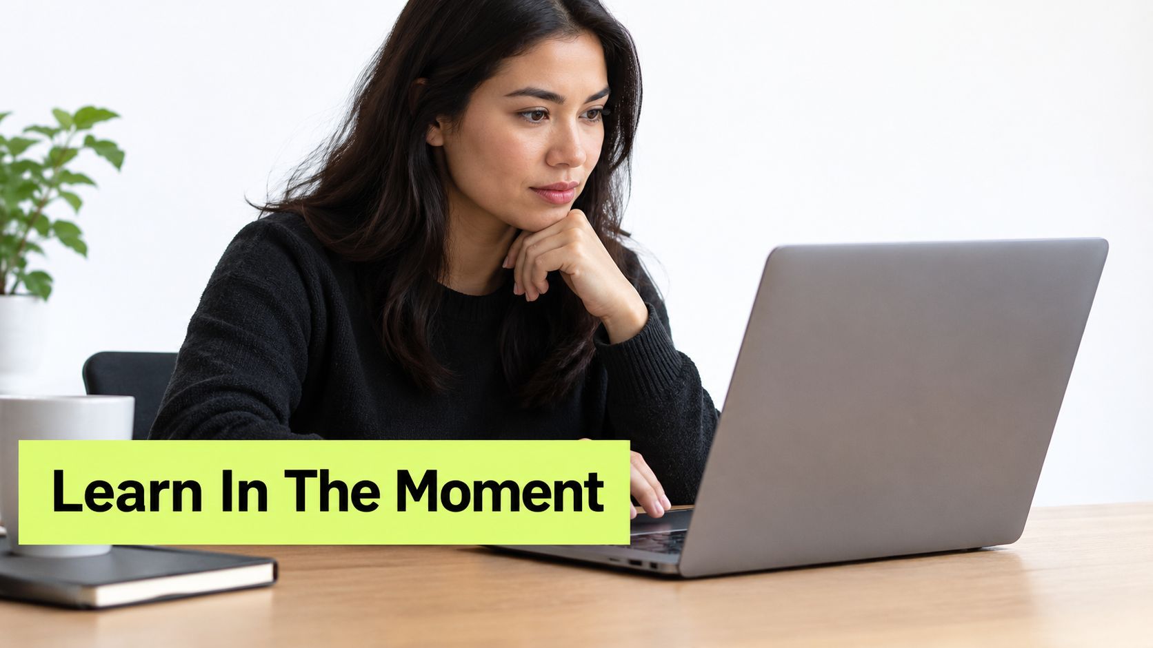 A woman working on a laptop with a green overlay that says Learn In The Moment
