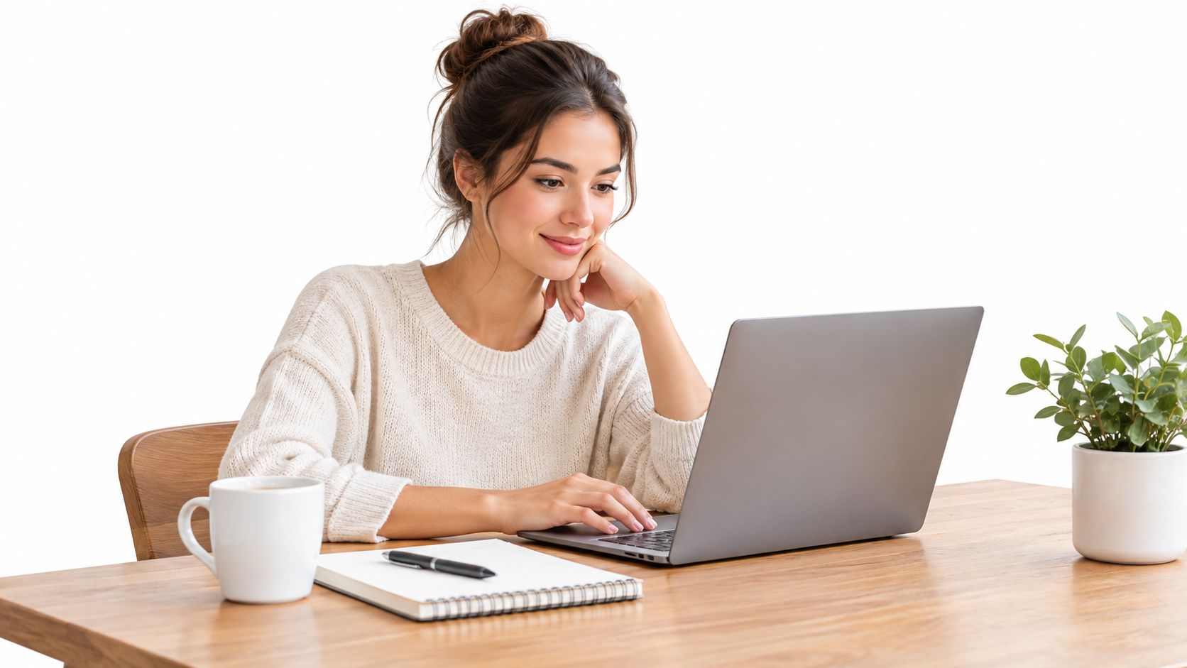 A woman working on a laptop at a wooden desk with a notebook and coffee.