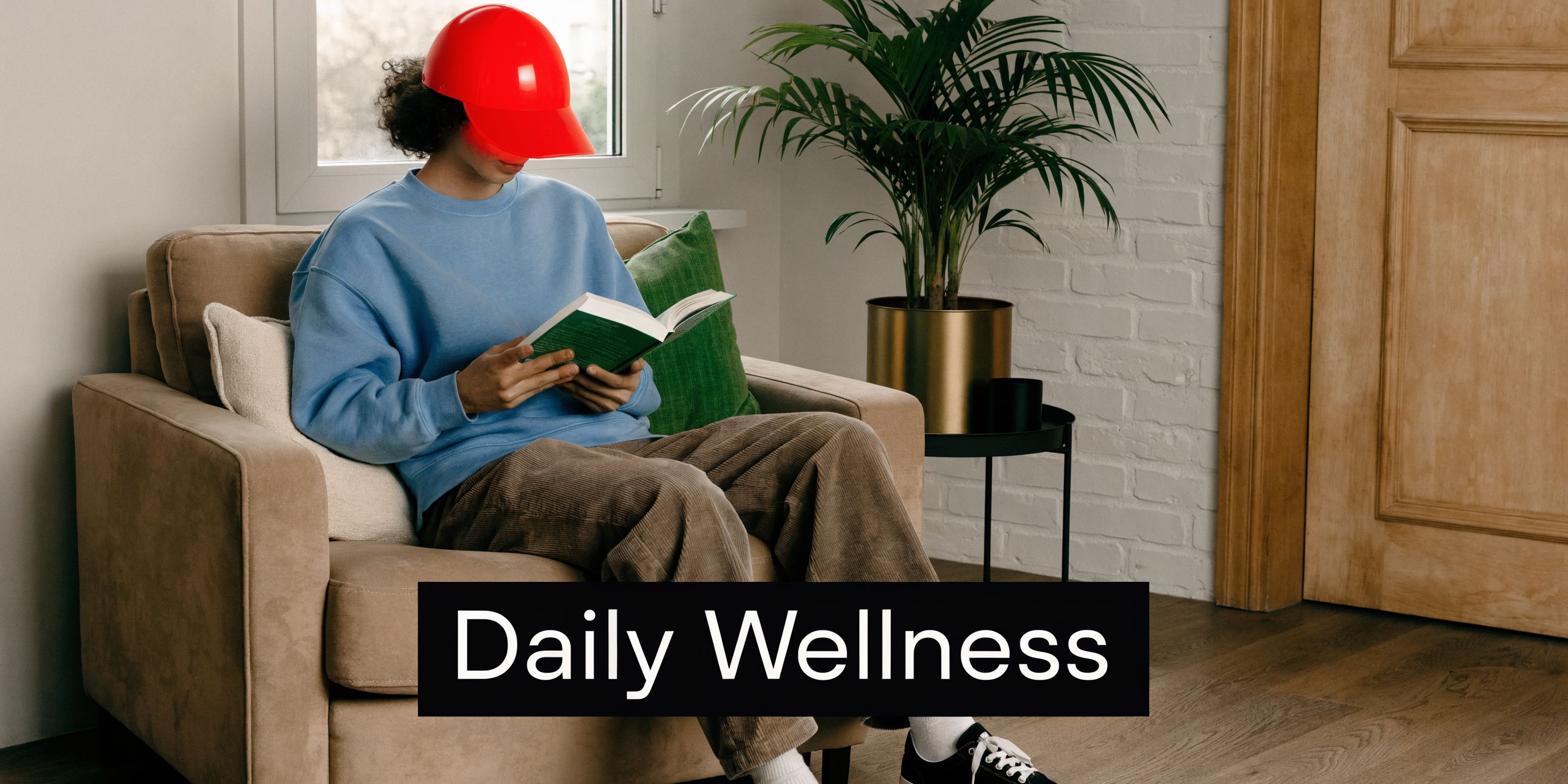 A person wearing a red light therapy cap while reading a book in a comfortable armchair