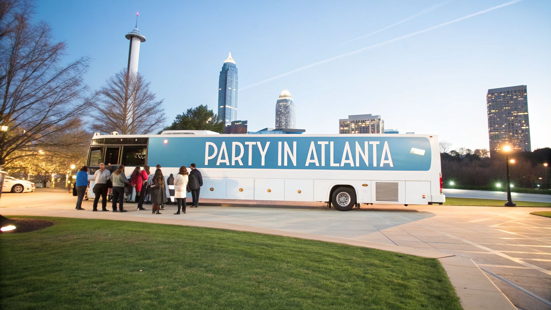 People gather around a white party bus in Atlanta with a distinctive city skyline in the background.