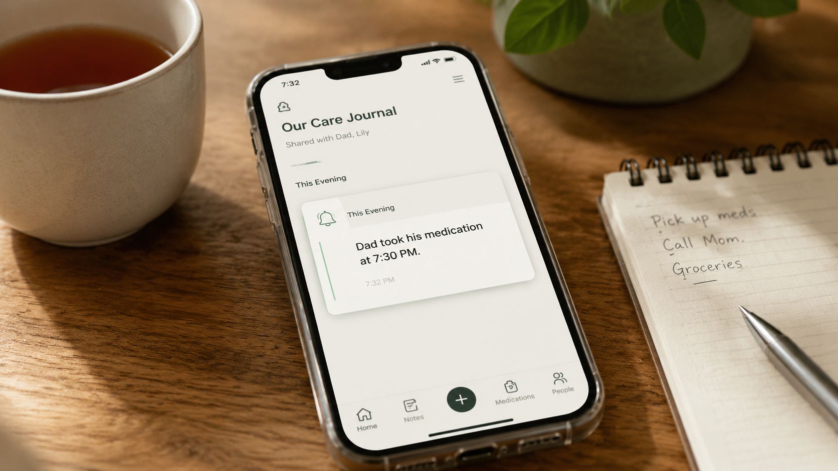 Un smartphone affichant une application de journal de soins quotidien partagé posé sur une table en bois.