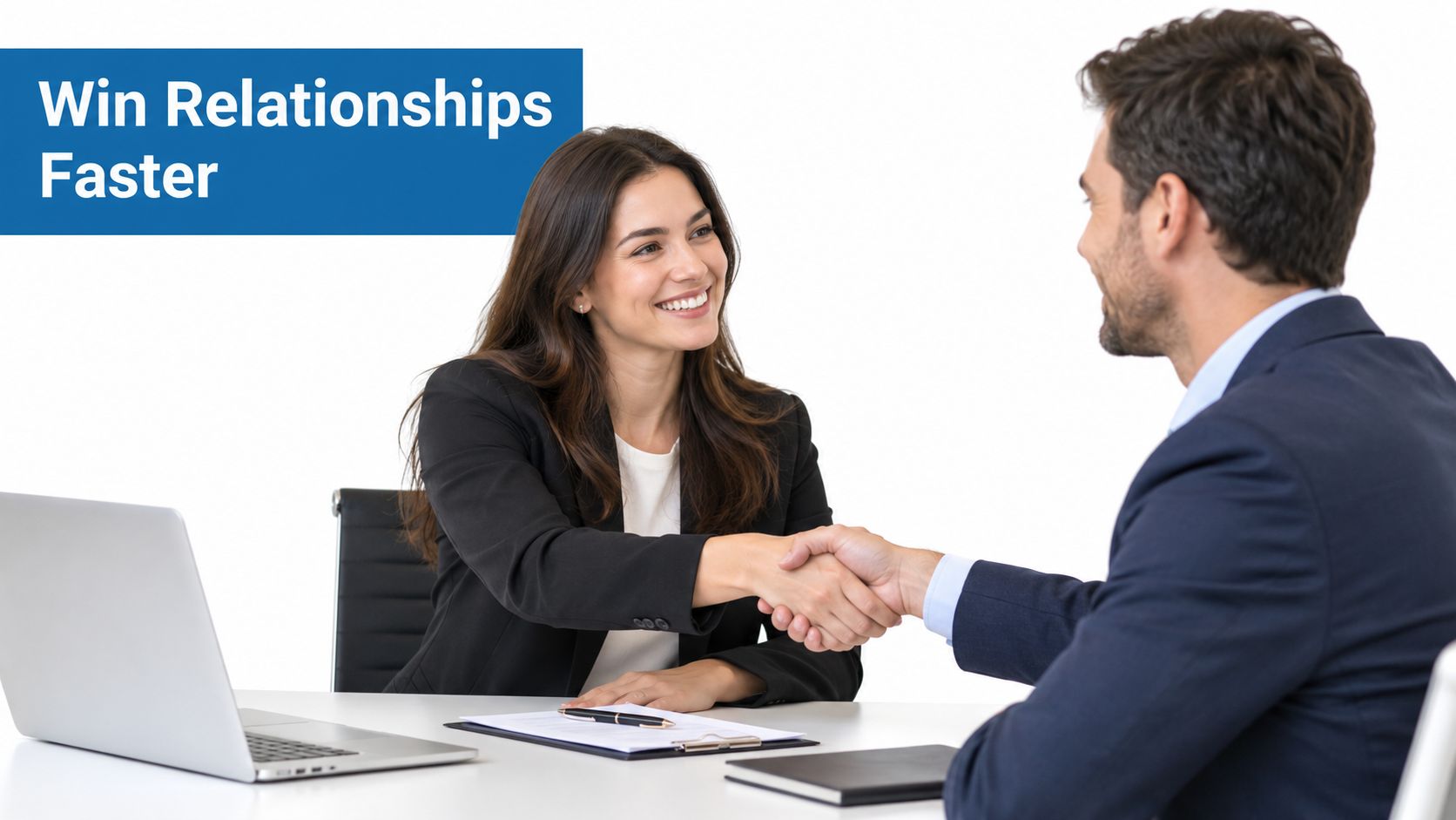 A professional man and woman in business attire shaking hands over a desk with a laptop.
