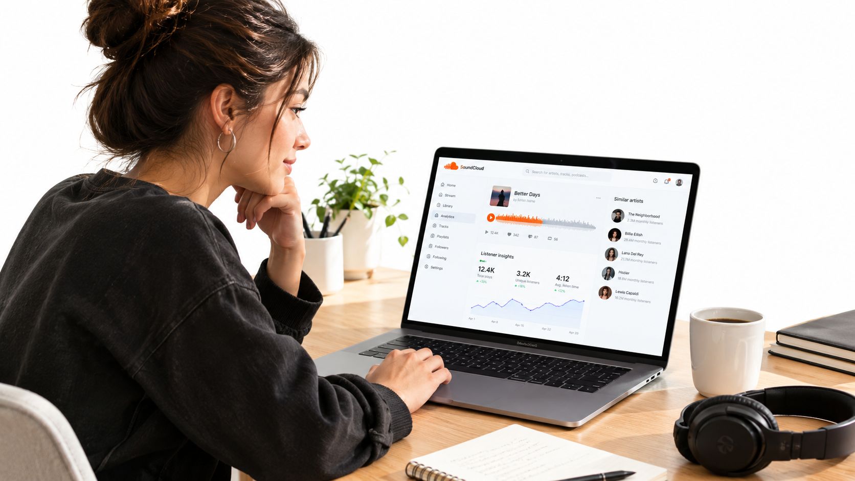 A young woman sits at a desk looking at music streaming analytics on her laptop screen.