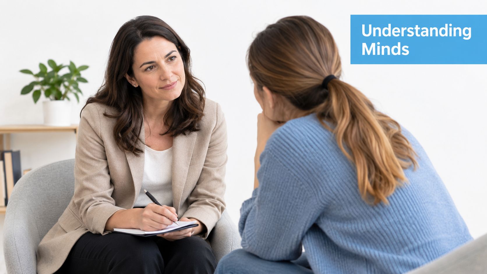 A professional therapist in a blazer taking notes while listening to her client during a session.