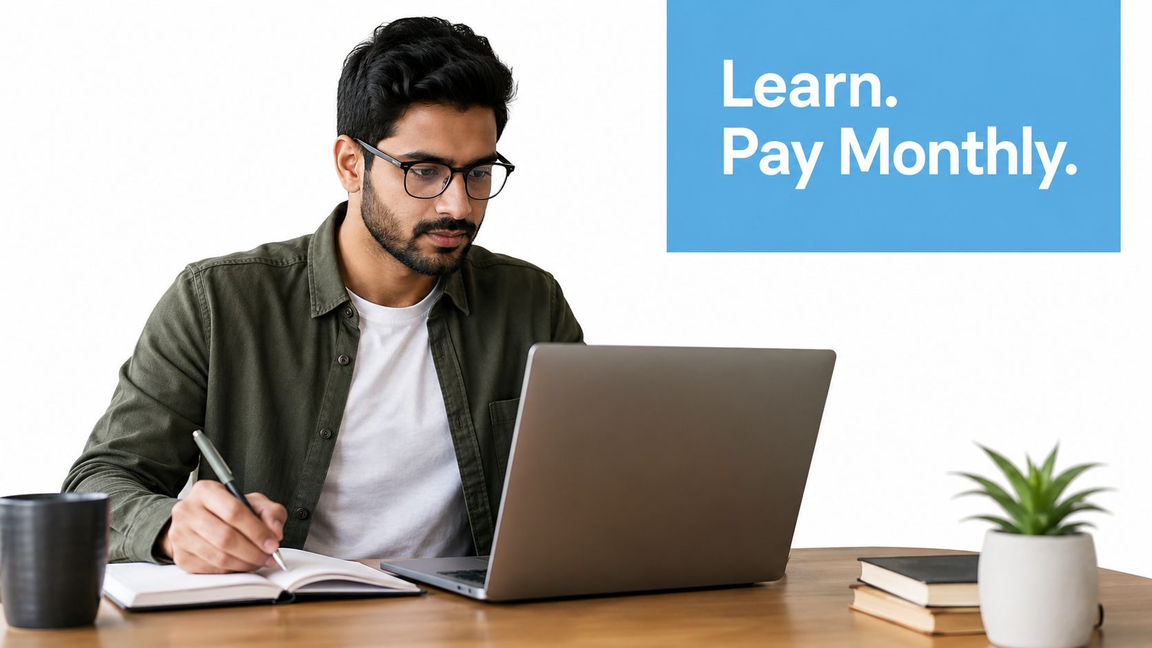 A focused man wearing glasses takes notes in a journal while working on his laptop at home.