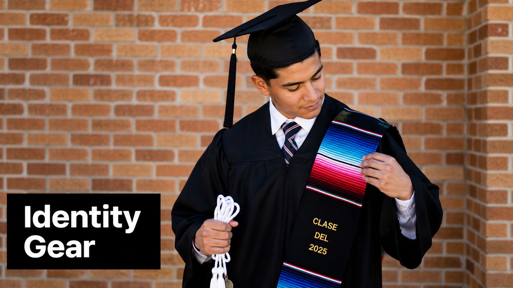 A male graduate student wearing a traditional black cap and gown with a colorful serape graduation stole.