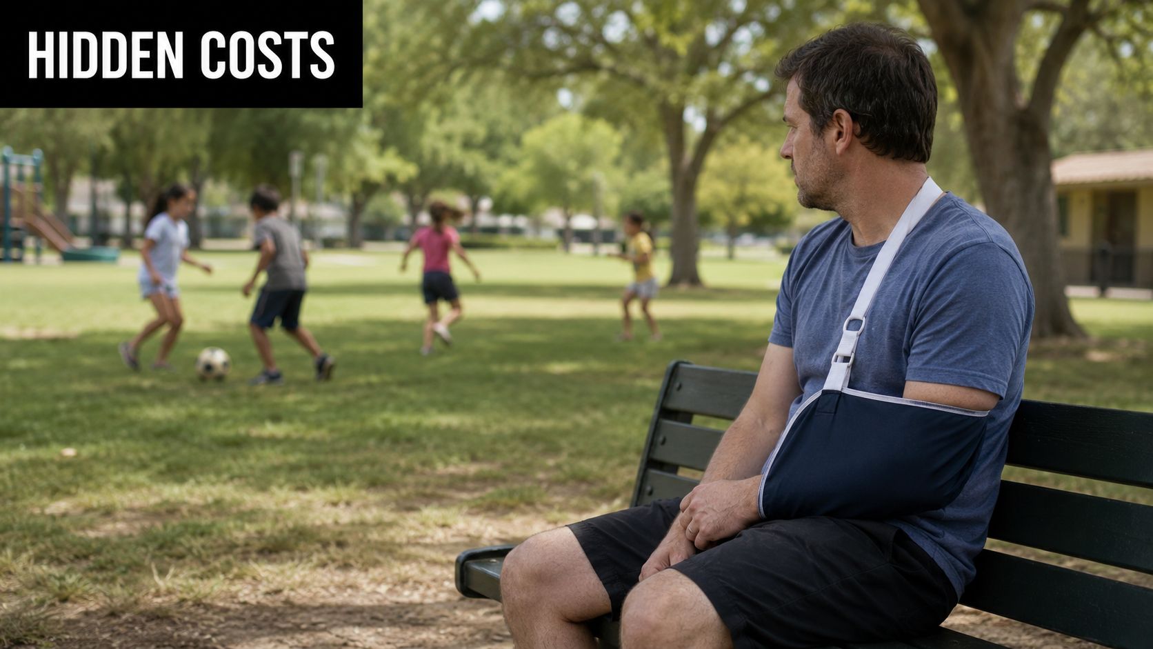 A man with an arm sling sitting on a park bench watching children playing soccer nearby.