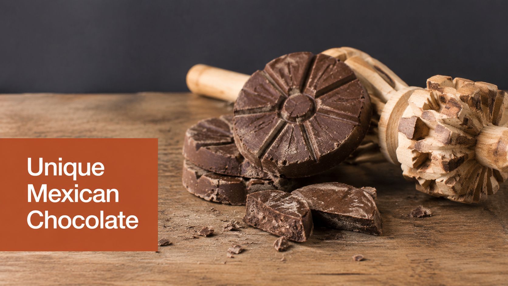 A close-up of traditional Mexican chocolate discs on a wooden surface with a wooden molinillo whisk nearby.