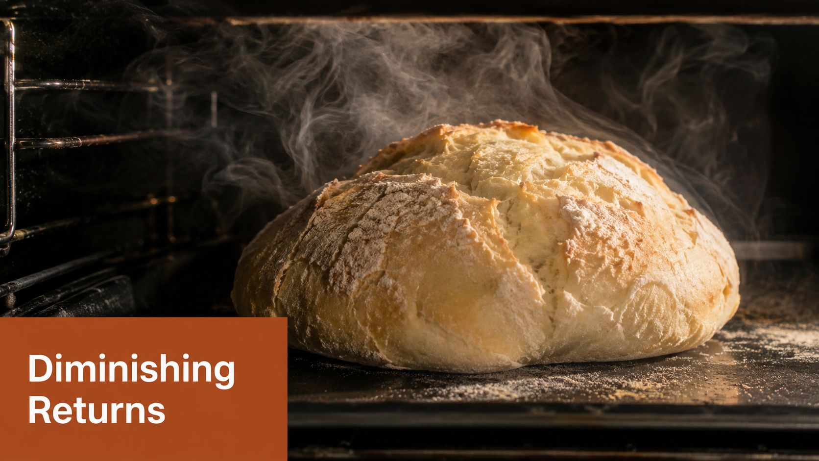 A freshly baked round loaf of bread resting on a black oven tray with steam rising